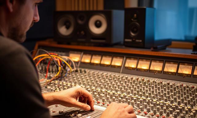 Ingeniero de sonido ajustando una consola analógica en el control de un estudio